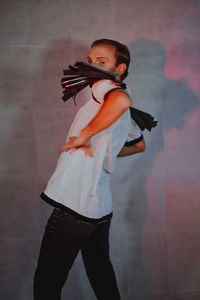 Side view of young man looking away against wall