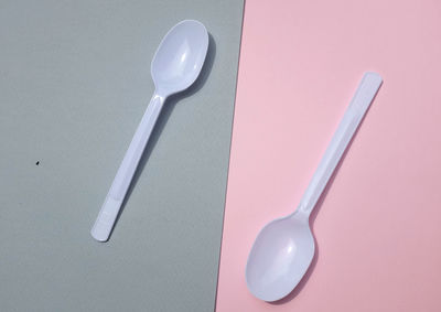 Flat lay a white plastic spoon on pink and gray paper background. minimal concept