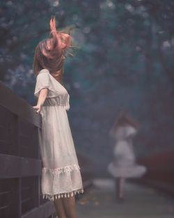 Side view of woman with tousled hair standing by railing at park