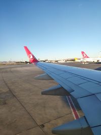 Airplane flying over airport runway against clear blue sky