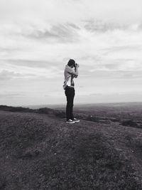 Man photographing through camera while standing on mountain against sky
