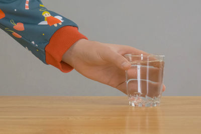 Close-up of hand holding drink on table