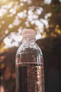 Close-up of water bottle against trees