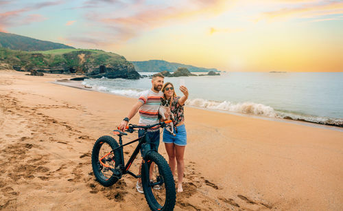Couple with fat bike taking a selfie with their dog on the beach