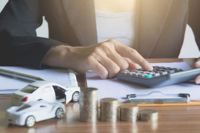 Midsection of businesswoman doing calculation at desk in office