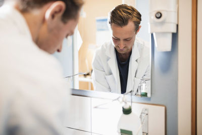 Mirror reflection of male doctor in hospital bathroom