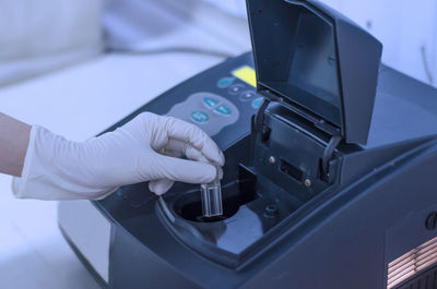 Cropped hand of scientist wearing surgical glove holding test tube in laboratory