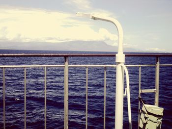 Railing by sea against sky