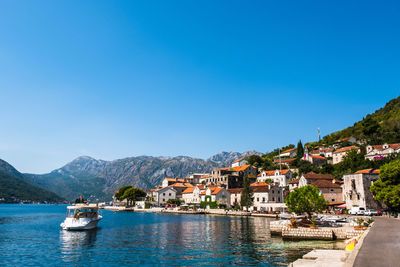 Scenic view of river amidst buildings against clear blue sky