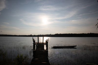 Pier over lake against sky during sunset