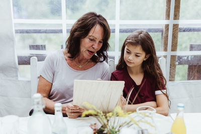 Grandmother and granddaughter looking at menu while sitting in restaurant