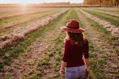 Rear view of woman wearing hat while standing on land