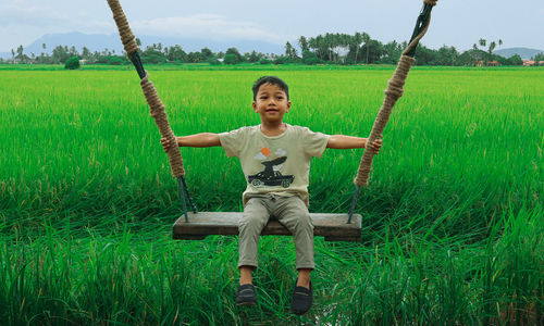 Portrait of boy sitting on grassy field