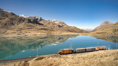 Small freight train on rails near a high mountain lake in the swiss alps