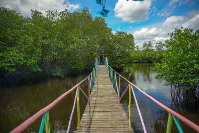 Footbridge over lake against sky