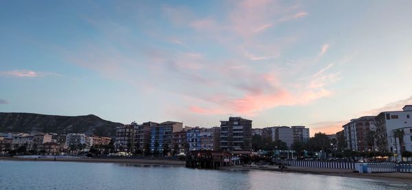 River amidst buildings against sky at sunset