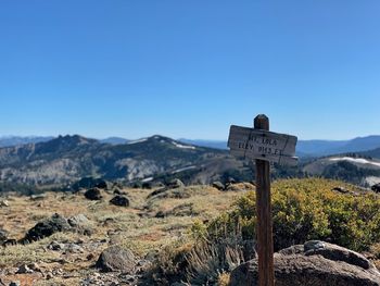 Information sign on mountain against clear blue sky