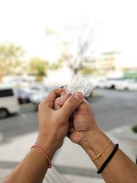 Cropped hands of man holding plastic against defocused background