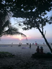 Silhouette people on beach against sky during sunset