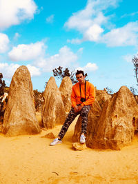 Man standing on rock against sky