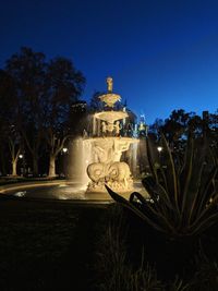 Statue in park against clear blue sky at night