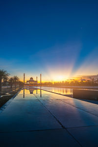 Scenic view of swimming pool against buildings during sunset