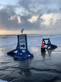 Lifeguard hut on beach against sky during sunset