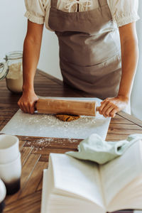 Midsection of a woman rolling dough for cookies at domestic kitchen