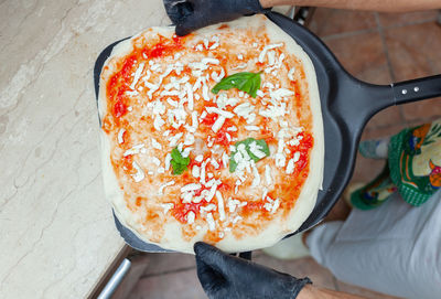 Cooking italian pizza margherita with basil.