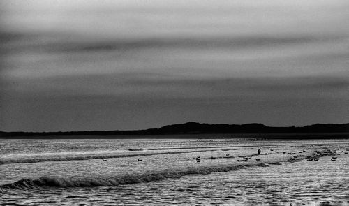 View of calm beach against cloudy sky