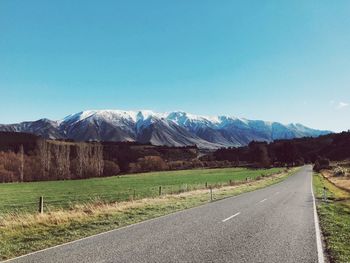 Road by mountains against clear blue sky