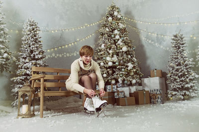 An adult woman in the new year at the skating rink ties her skates  next to the christmas tree