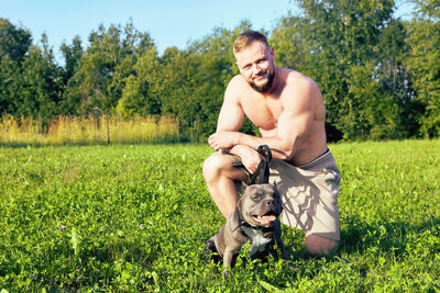 Portrait of young man with dog on field