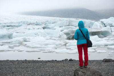 Tourist admiring the floating icebergs drifting in the water in fjallsarlon glacier lagoon, iceland