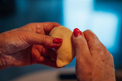 Close shot of a woman's hands with red nails making polish dumplings.