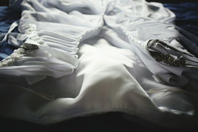 Close-up of wedding dress on bed