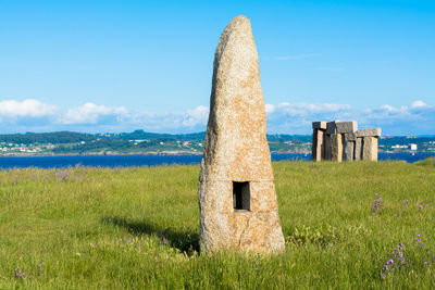 Built structure on field by sea against sky