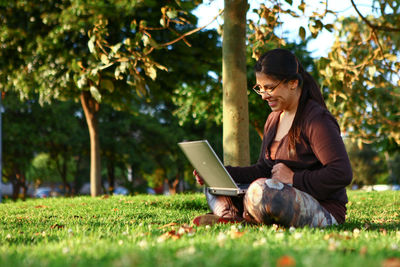 Woman using laptop while sitting on grass