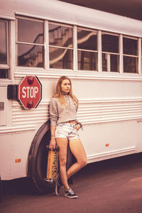 Full length of young woman leaning on bus