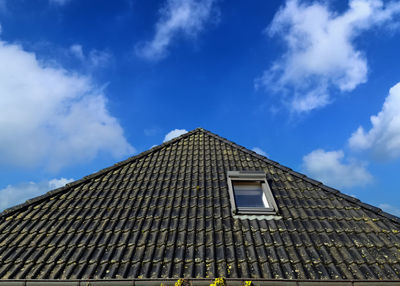 Roof window in velux style with black roof tiles