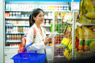 Portrait of smiling young woman standing at supermarket