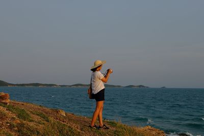 Woman standing by sea against sky