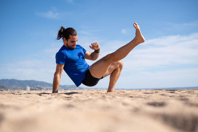 Low section of woman exercising at beach