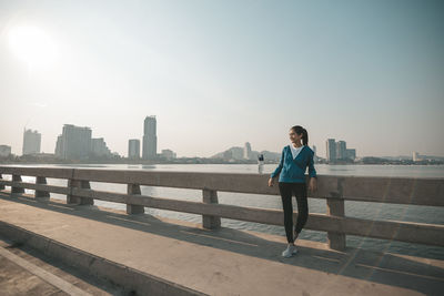 Full length of man standing on railing against cityscape