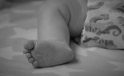 Low section of baby lying on bed