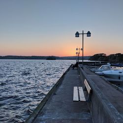 Street by pier against sky during sunset