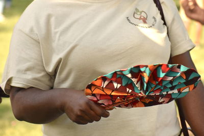 Midsection of man holding multi colored umbrella