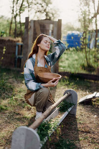 Woman with head in hand crouching in farm