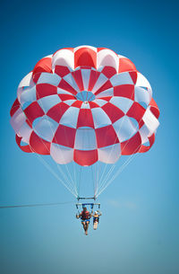 Low angle view of person paragliding against clear blue sky