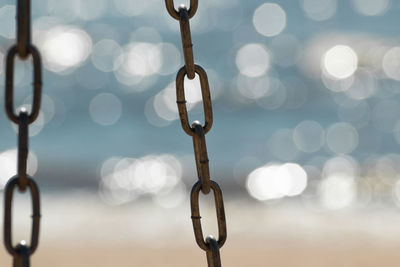 Metal chain from a swing isolated on sparkle sea and sand at the beach